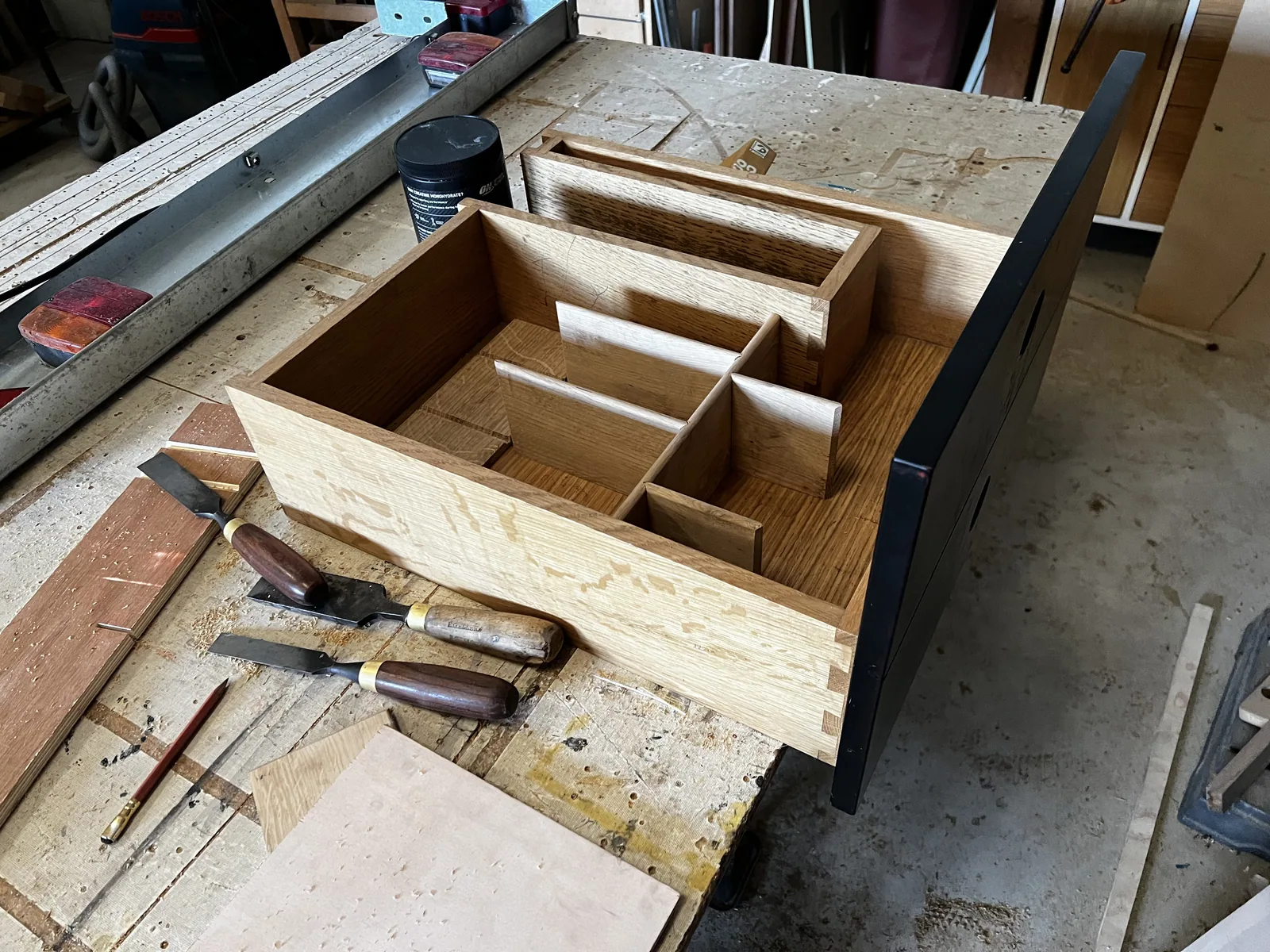 Oak drawer carcase with fitted dividers under construction, chisels laid alongside