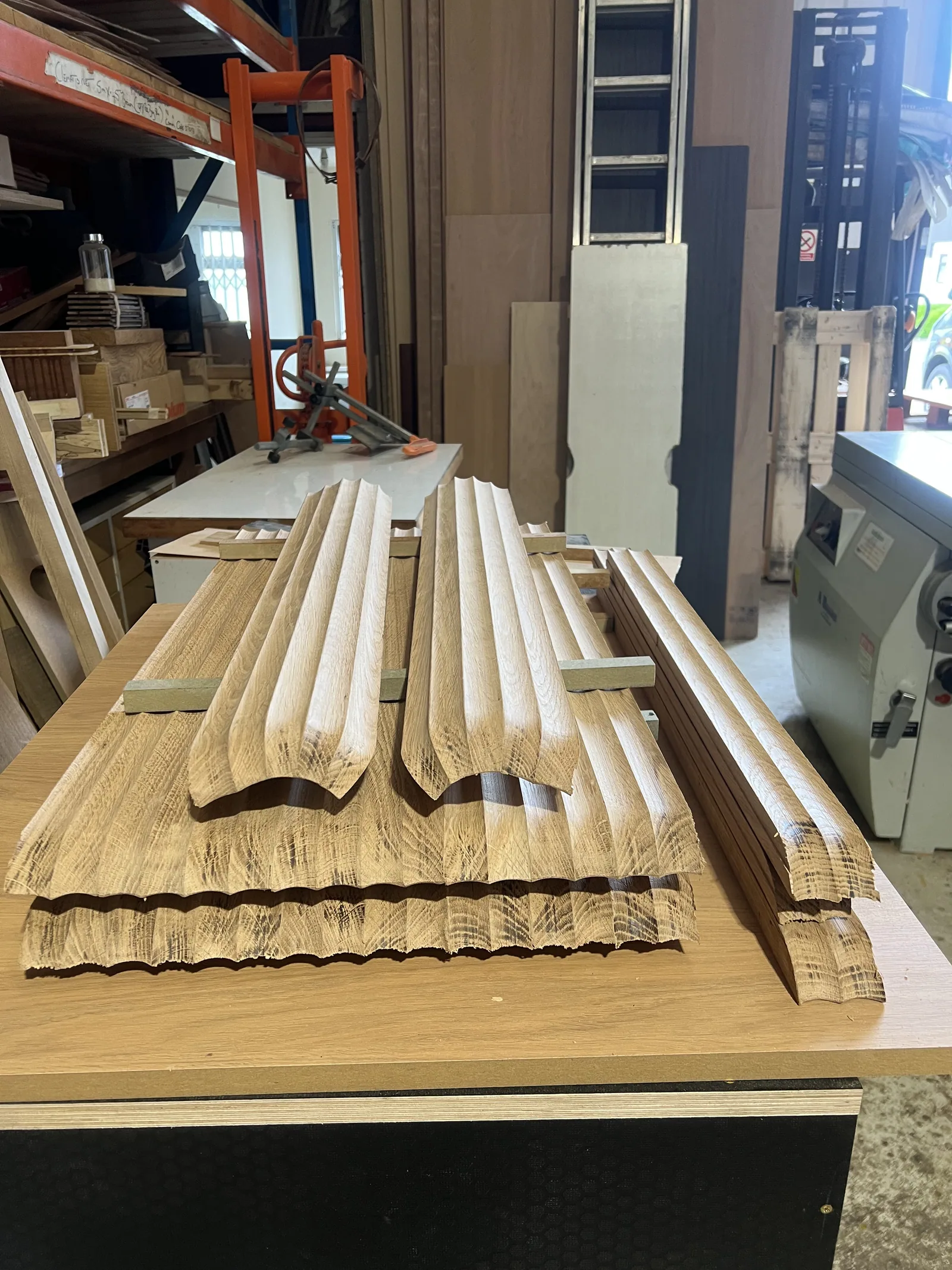 Machined fluted oak mouldings stacked on the workshop bench